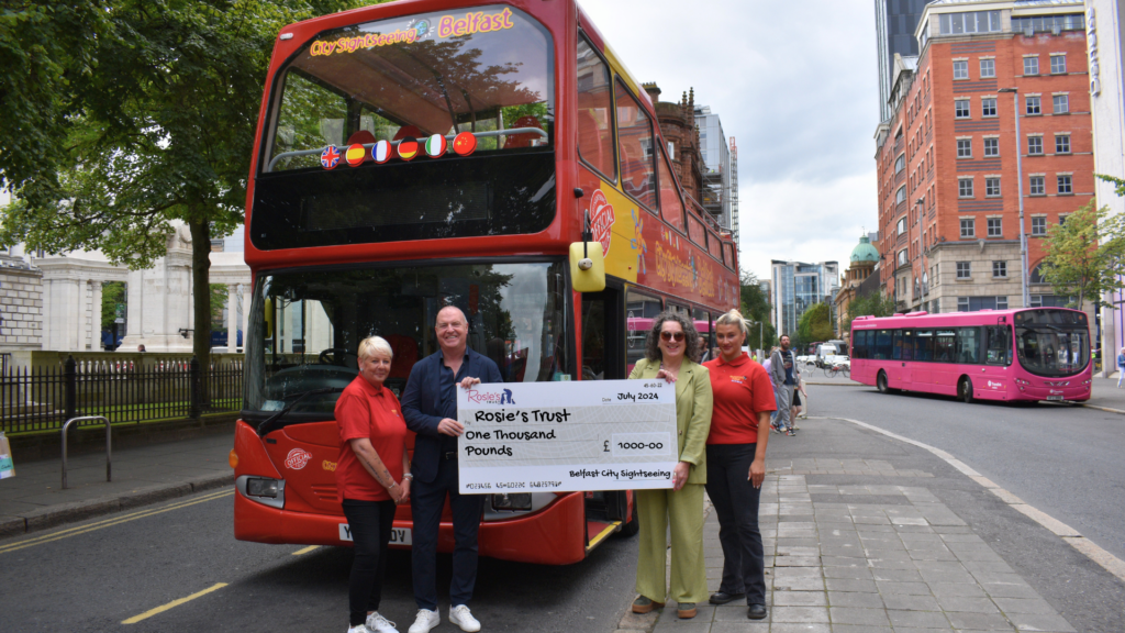 a Group holding large cheque in front of a bus